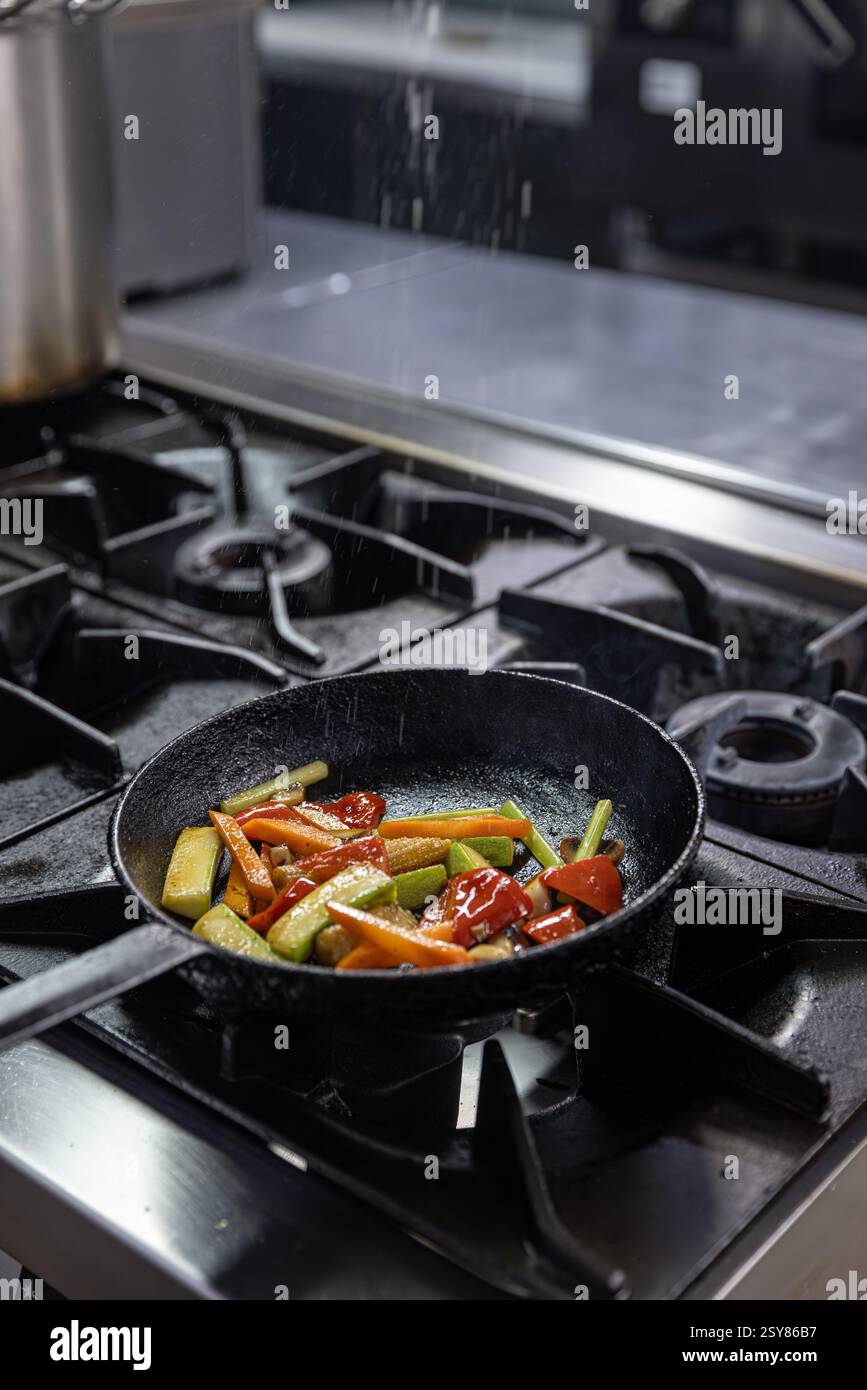 Verdure grigliate colorate cucinate in una padella su un piano cottura professionale in una cucina commerciale Foto Stock