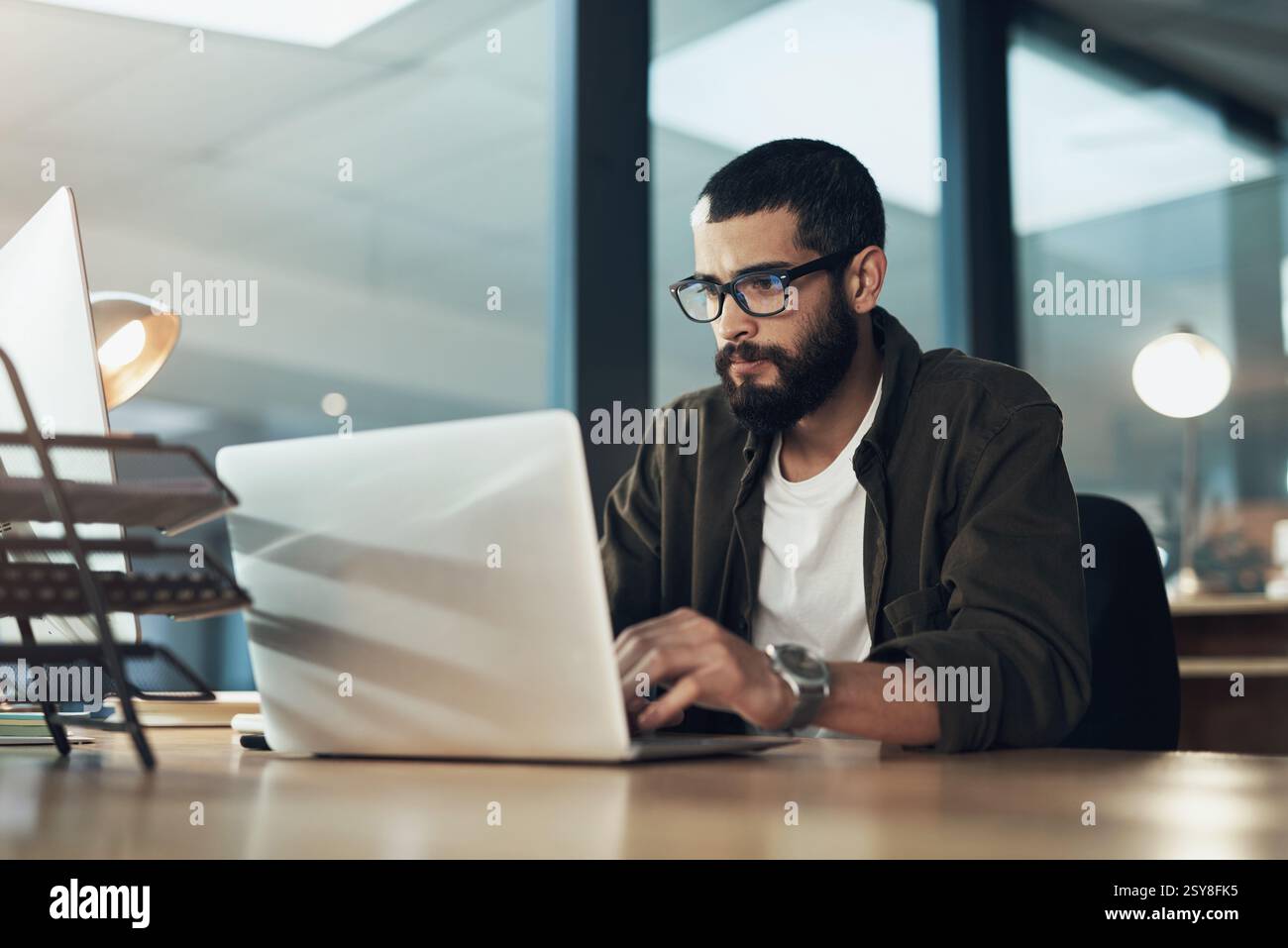 Laptop, digitazione e ricerca con un uomo d'affari in ufficio per Web designer, strumenti ux o pianificazione. Homepage di codifica, serata e sviluppatore con la persona in Foto Stock