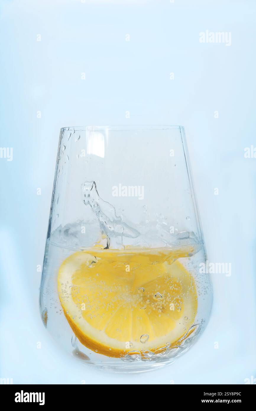 limone in un bicchiere di soda. il limone è caduto in un bicchiere di bibita e gli schizzi volano il limone cade nell'acqua. cocktail, limonata fatta in casa Foto Stock