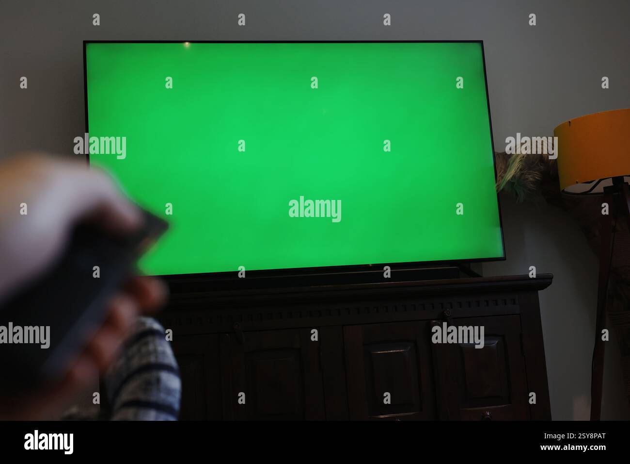 tv con schermo verde. uomo con telecomando che accende la tv cambiando canale. schermata verde per la modifica. Foto Stock