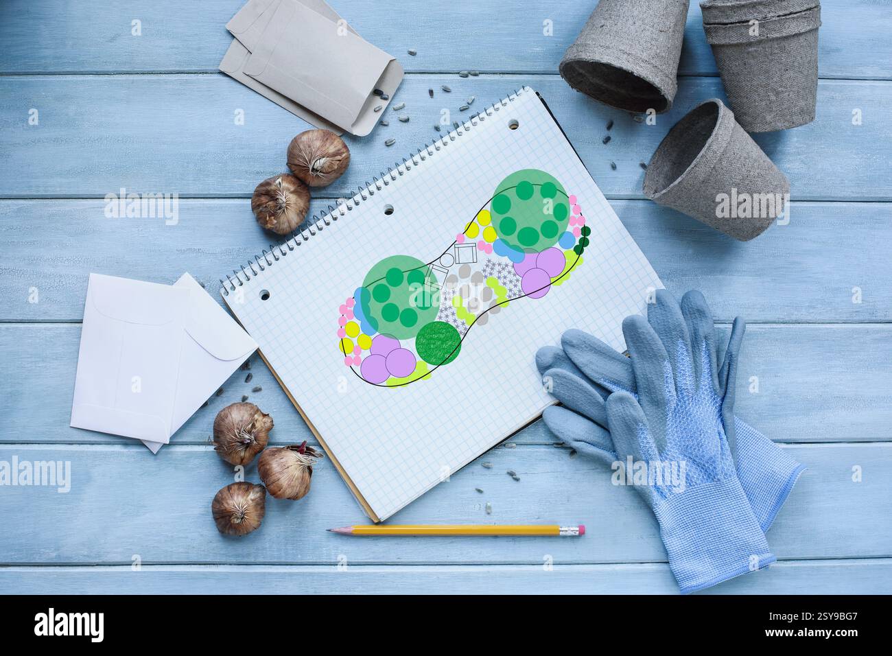 Quaderno a griglia con diario di giardinaggio con pianta a aiuola circondato da guanti da giardino, matita, semi, bulbi di fiori, buste e vasi di torba su un woo rustico Foto Stock