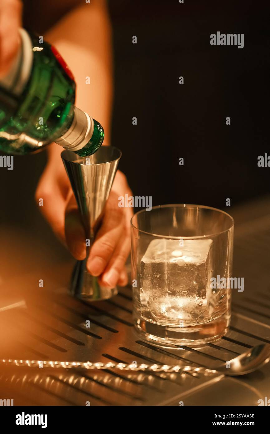 Mano del barista che versa alcol a jigger. Bartending e mixology Foto Stock