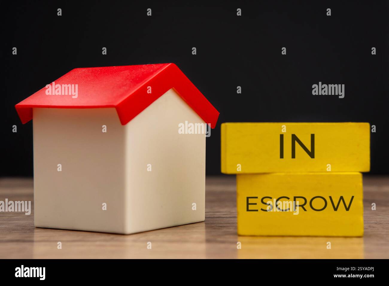 Una casa dei giocattoli con fino a due blocchi gialli impilati con le parole "IN DEPOSITO". Concetto di proprietà e proprietà immobiliari. Foto Stock