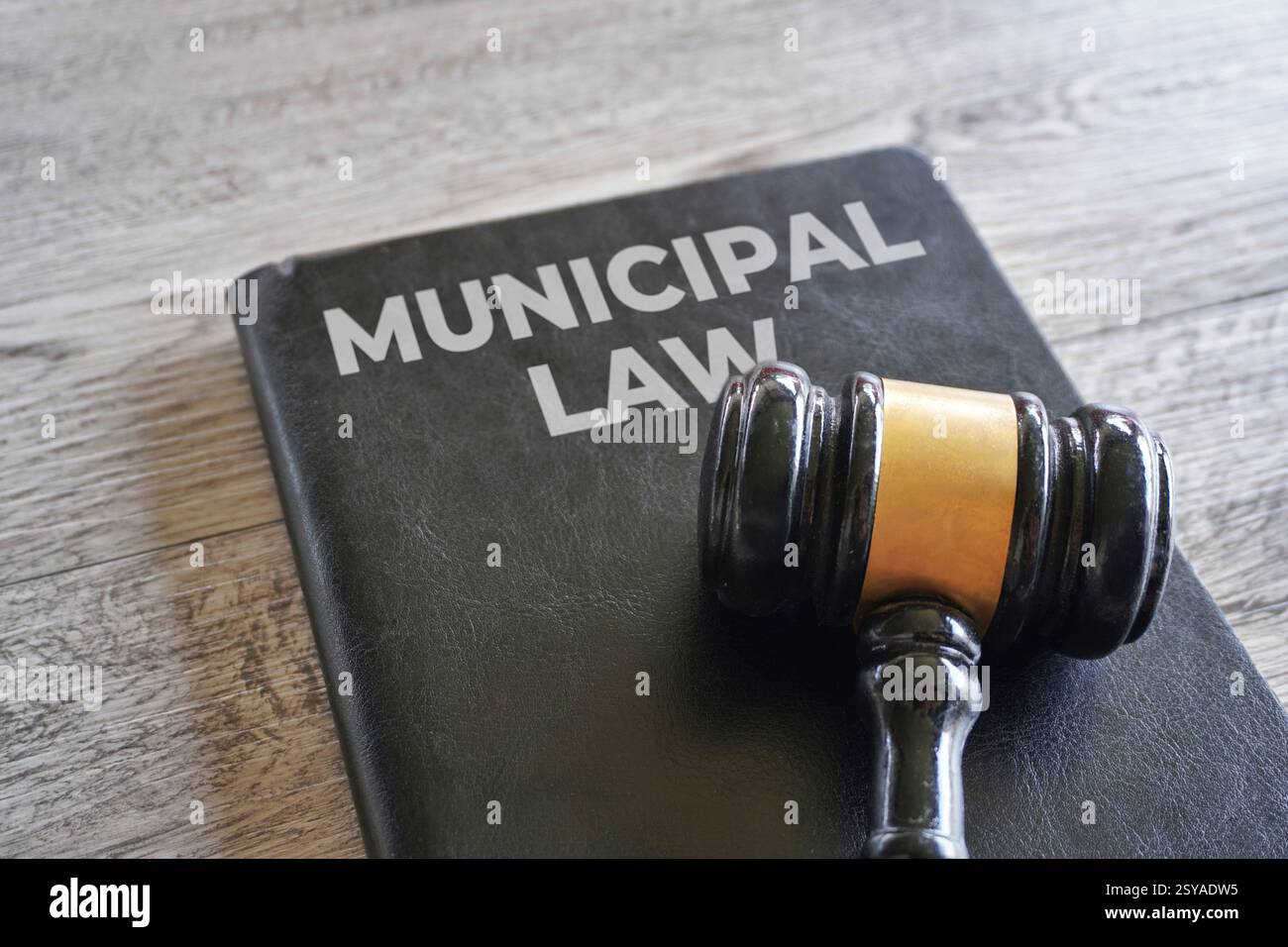 Un libro nero intitolato "LEGGE MUNICIPALE" con un martelletto di legno. Concetto di giustizia e diritto. Foto Stock