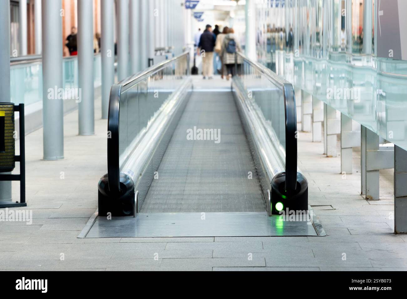 Una scena urbana contemporanea caratterizzata da un passaggio pedonale in movimento in una trafficata stazione dei trasporti pubblici con passeggeri irriconoscibili sullo sfondo. Foto Stock