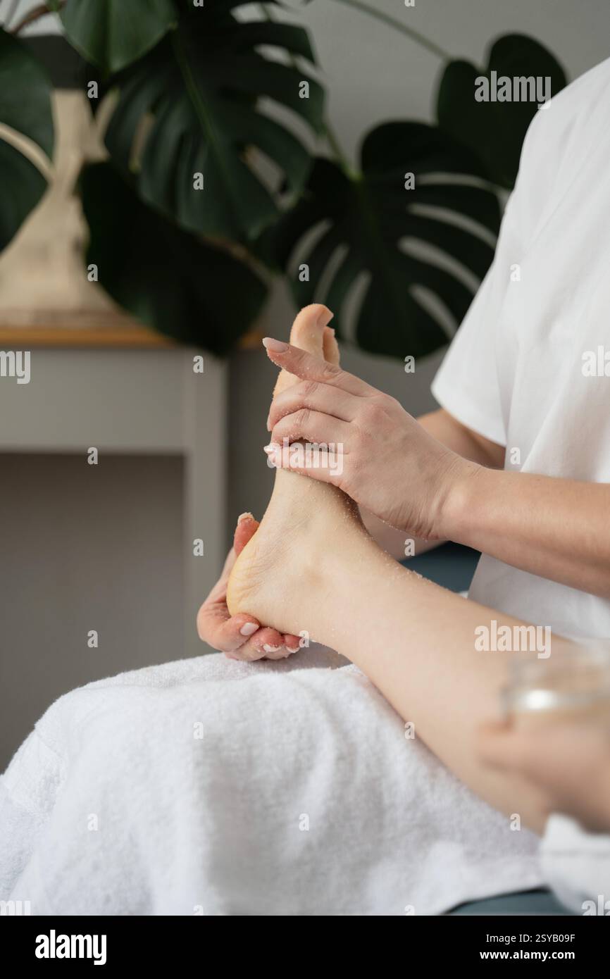 Una scena rilassante di una madre che fa un massaggio ai piedi delicato per sua figlia in un ambiente accogliente. Rappresentazione perfetta di legame familiare e cura di sé Foto Stock