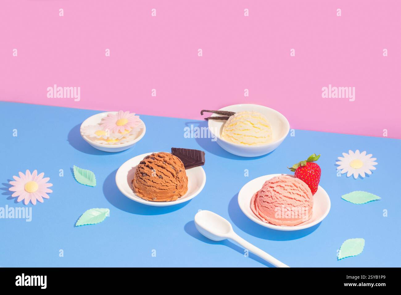 Quattro ciotole di gelato al gusto di vaniglia, cioccolato e fragola, disposte su uno sfondo rosa e blu diviso con fiori di carta decorativi e. Foto Stock