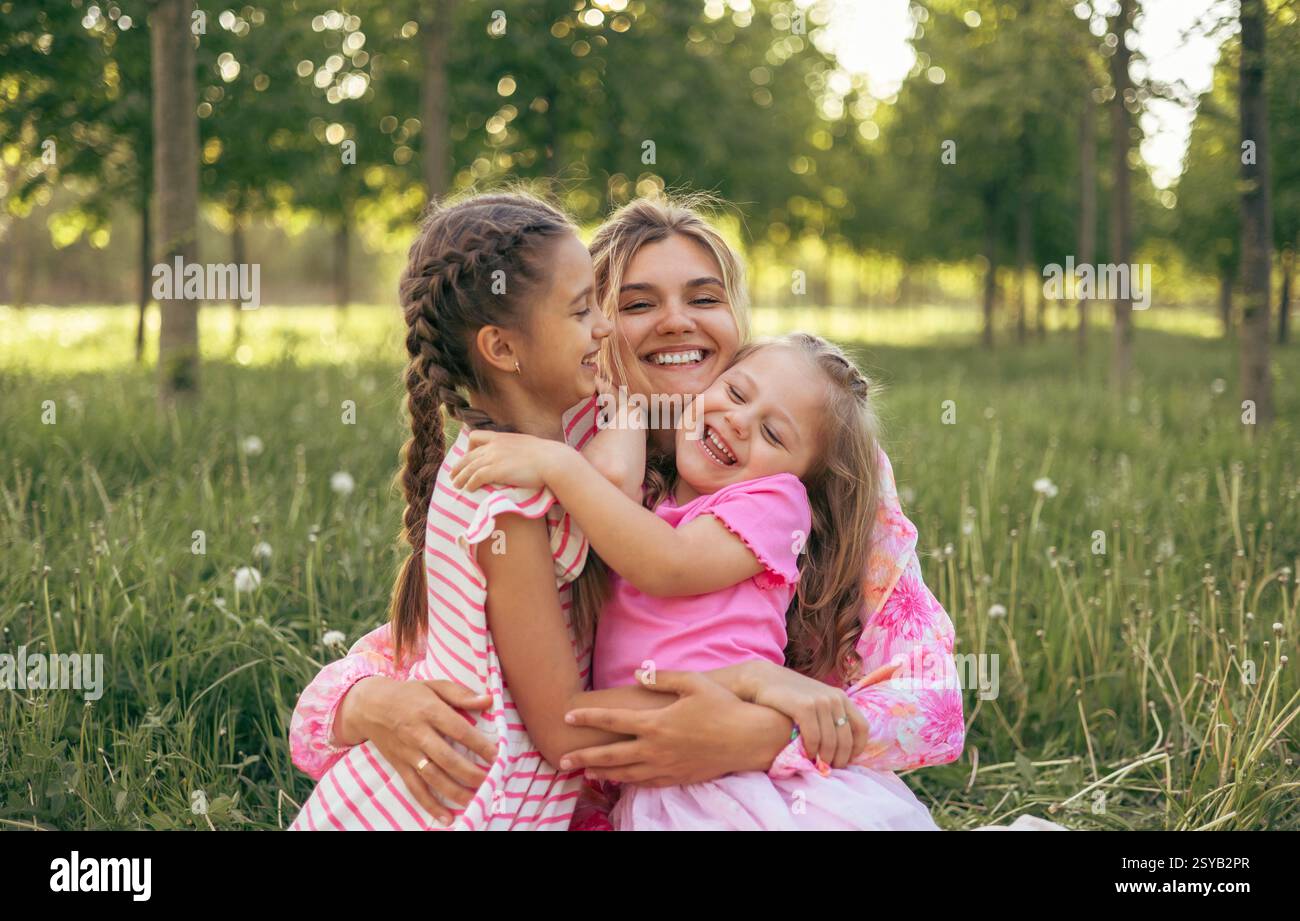 Una giovane madre e due figlie si divertono insieme all'aperto in estate. Valori familiari Foto Stock