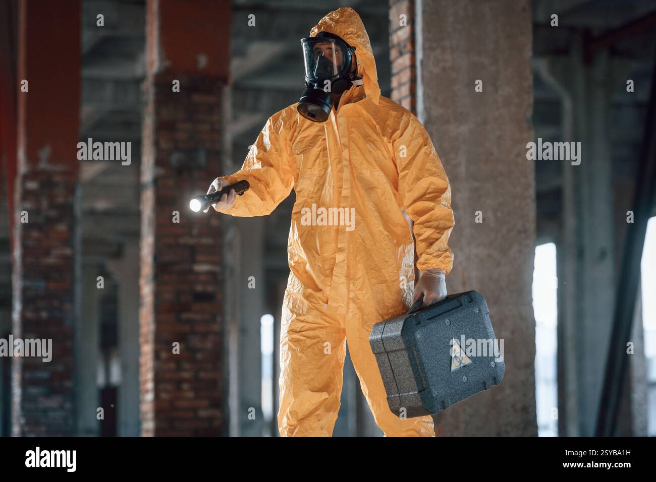 Uomo vestito con una tuta di protezione chimica tra le rovine dell'edificio post apocalittico. Foto Stock