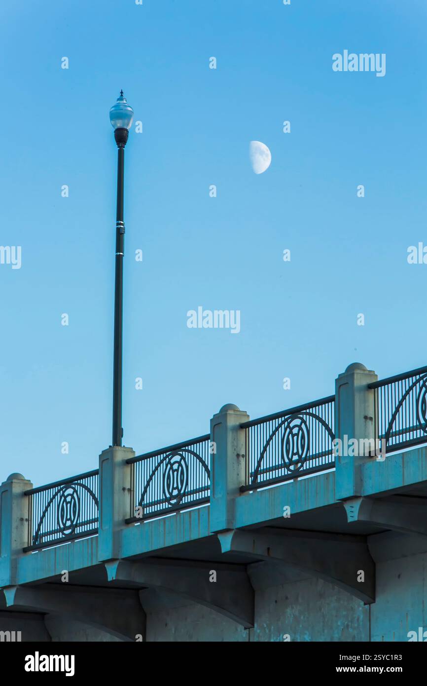 Palo per illuminazione stradale con un semaforo sulla parte superiore. Una luna piena è nel cielo Foto Stock