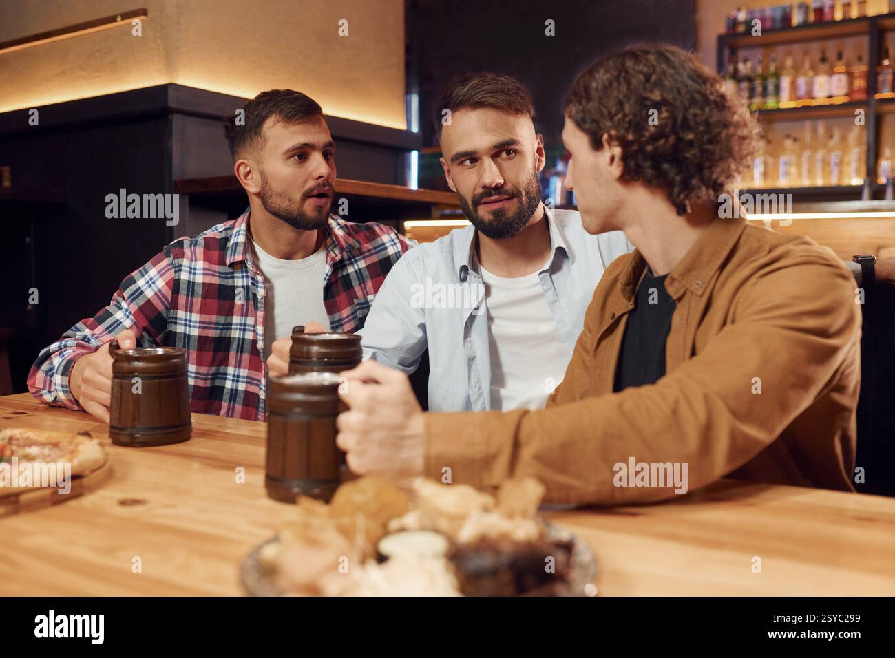 Avere una conversazione. Tre amici sono al bar a bere birra e a divertirsi. Foto Stock