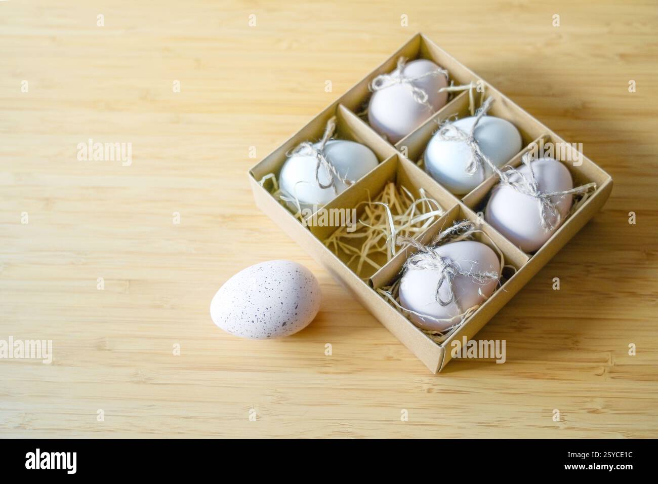 Scatola di cartone per sei uova, una macchiata è stesa fuori su un tavolo di bambù, concetto di uovo di Pasqua o pensare fuori dalla scatola ed essere diversa, copia Foto Stock