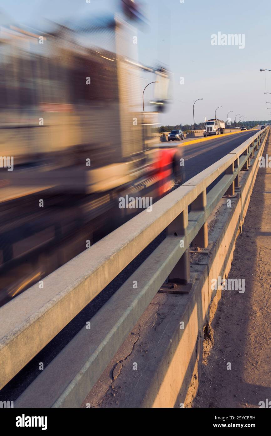 Immagine sfocata di un camion e di una persona che cammina su una strada. Il carrello è sullo sfondo e la persona è in primo piano Foto Stock