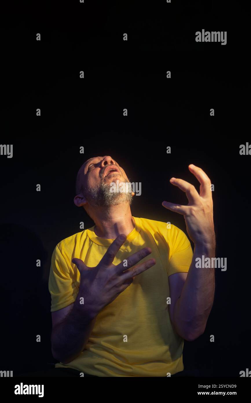 Uomo maturo, anni 50, calvo e barbuto, con indosso una camicia gialla, che mostra preoccupazione, paura o disagio. Concetto di assistenza psicologica. Brasile Foto Stock