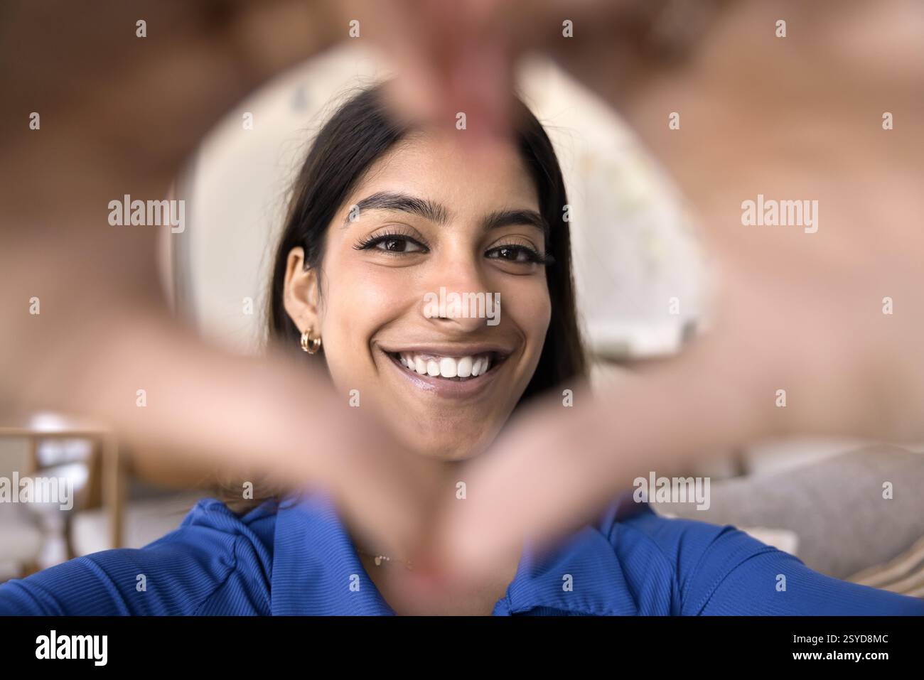 Allegra giovane donna indiana che fa il simbolo dell'amore con le dita unite Foto Stock