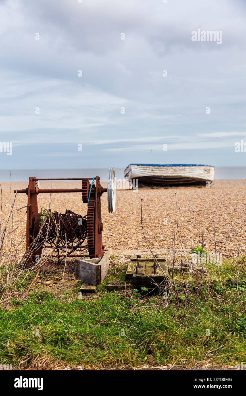 Barca da pesca abbandonata sulla spiaggia di Aldeburgh in un pomeriggio di febbraio con Very Old Rusted Winch in Foreground Foto Stock