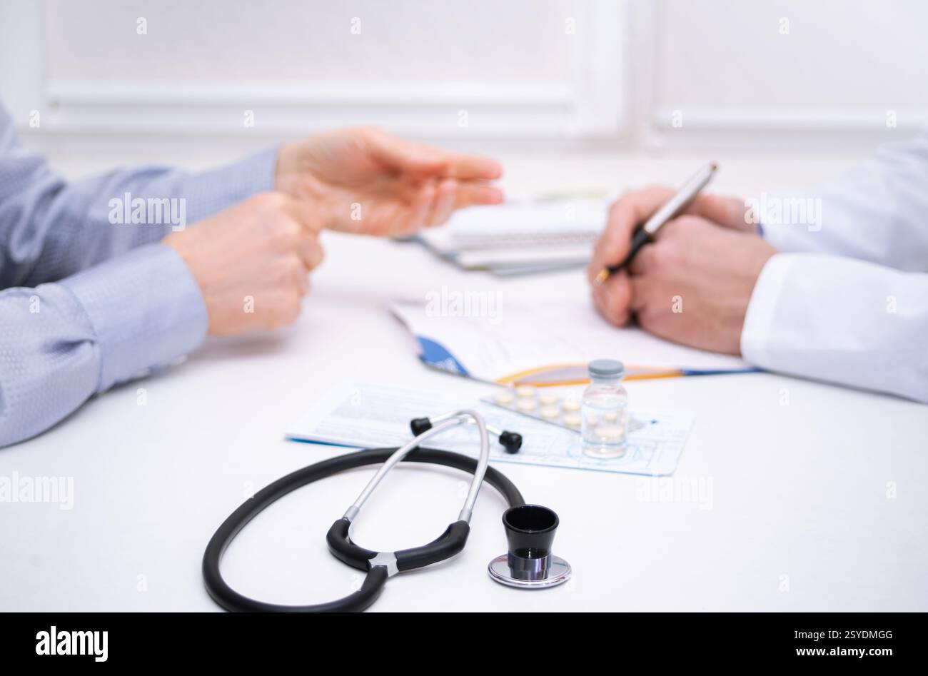 Medico discute problemi di salute con un paziente, rivedendo note e farmaci in uno studio medico durante un appuntamento. Foto Stock