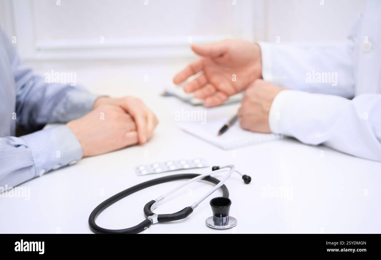 Medico discute problemi di salute con un paziente, rivedendo note e farmaci in uno studio medico durante un appuntamento. Foto Stock