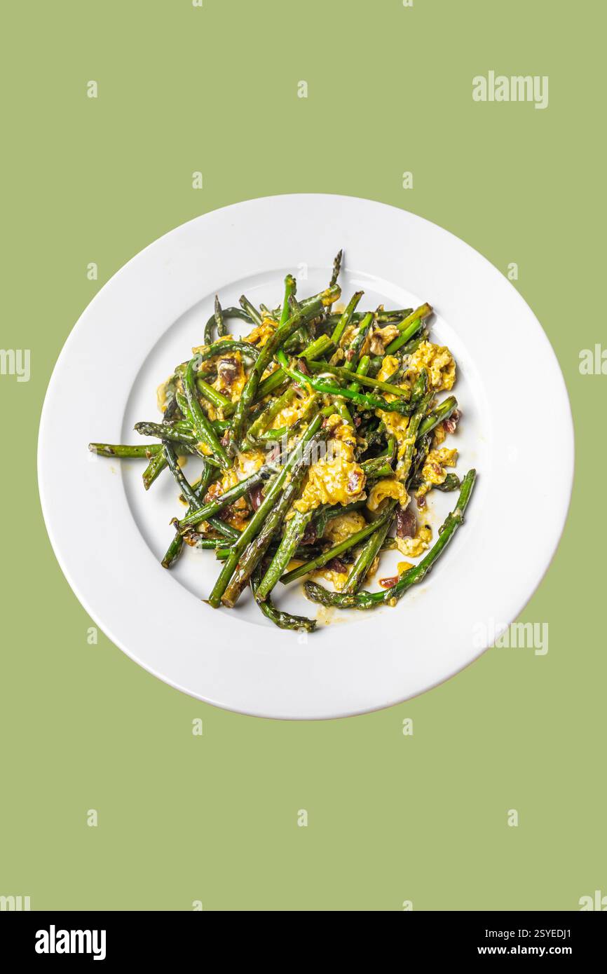 Squisita omelette di asparagi selvatiche servite su un piatto di ceramica bianca con sfondo verde Foto Stock
