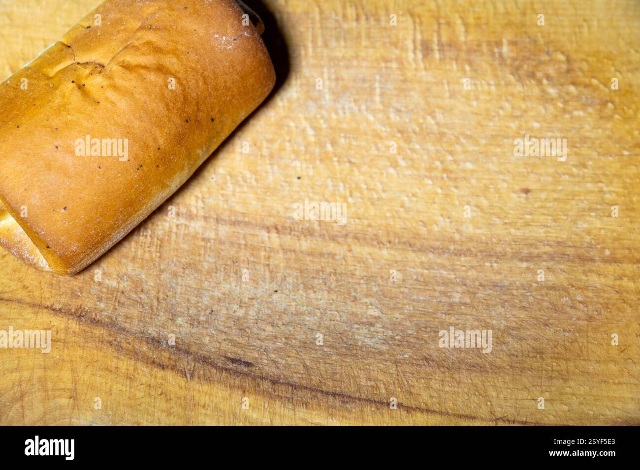 Su un tagliere di legno liscio viene posizionata una pagnotta calda di pane. La crosta è marrone dorato e presenta un aspetto fresco e fatto in casa. Perfetto per i servi Foto Stock