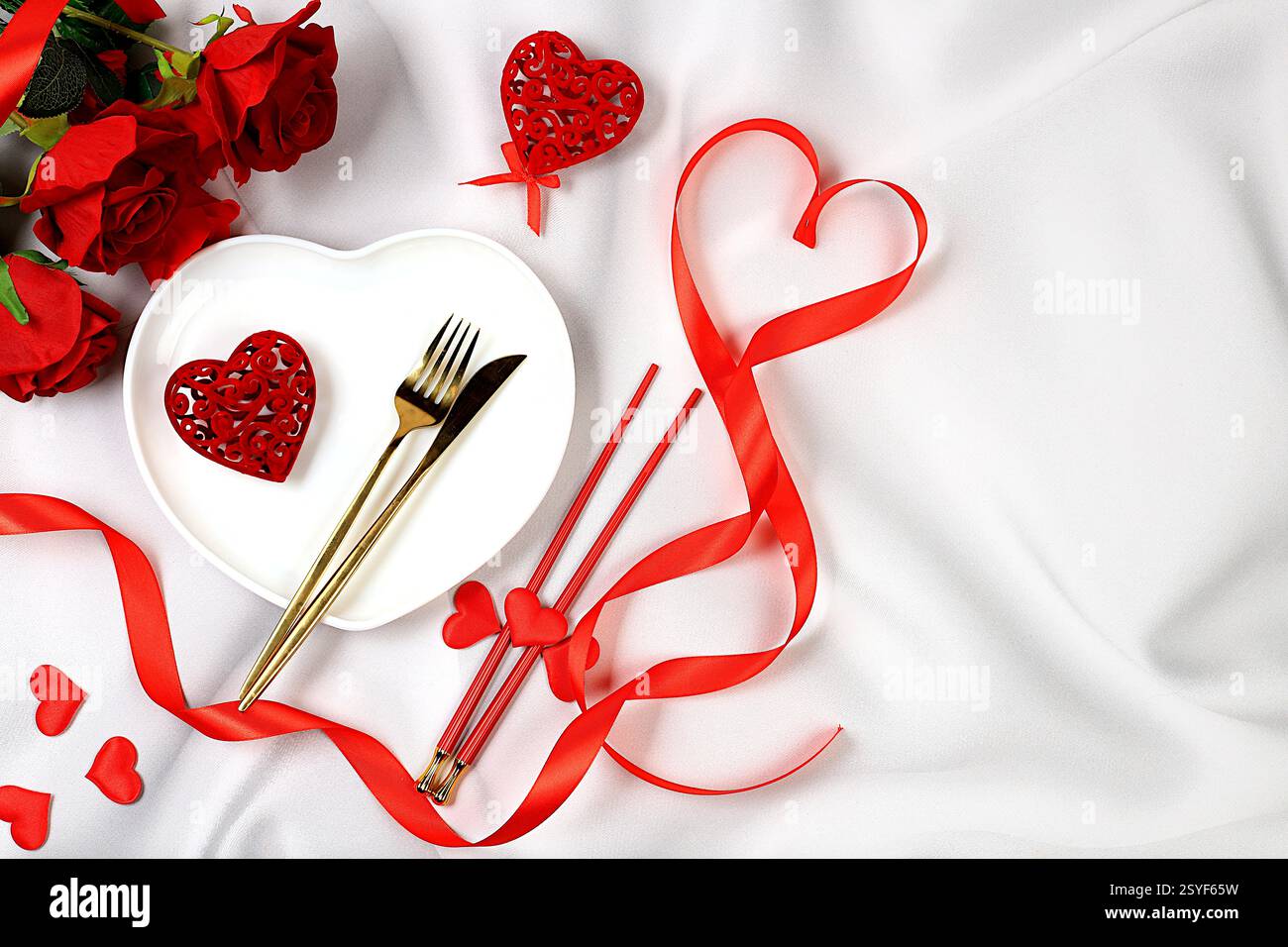Tavolo festivo, menu per San Valentino, posate con cuore su un piatto su sfondo di marmo, composizione festosa con bouquet di Foto Stock