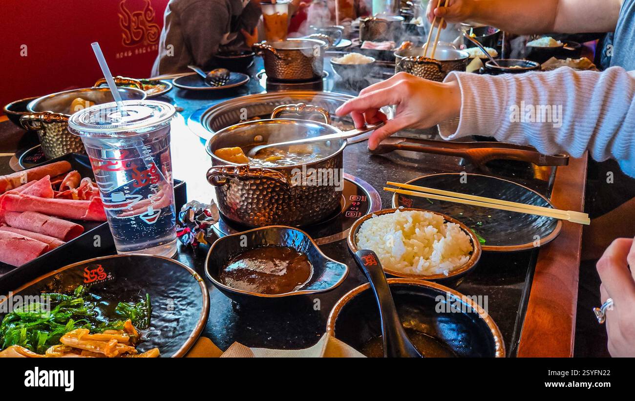 Gli amici possono gustare un pasto caldo con ingredienti freschi e brodo bollente. Foto Stock