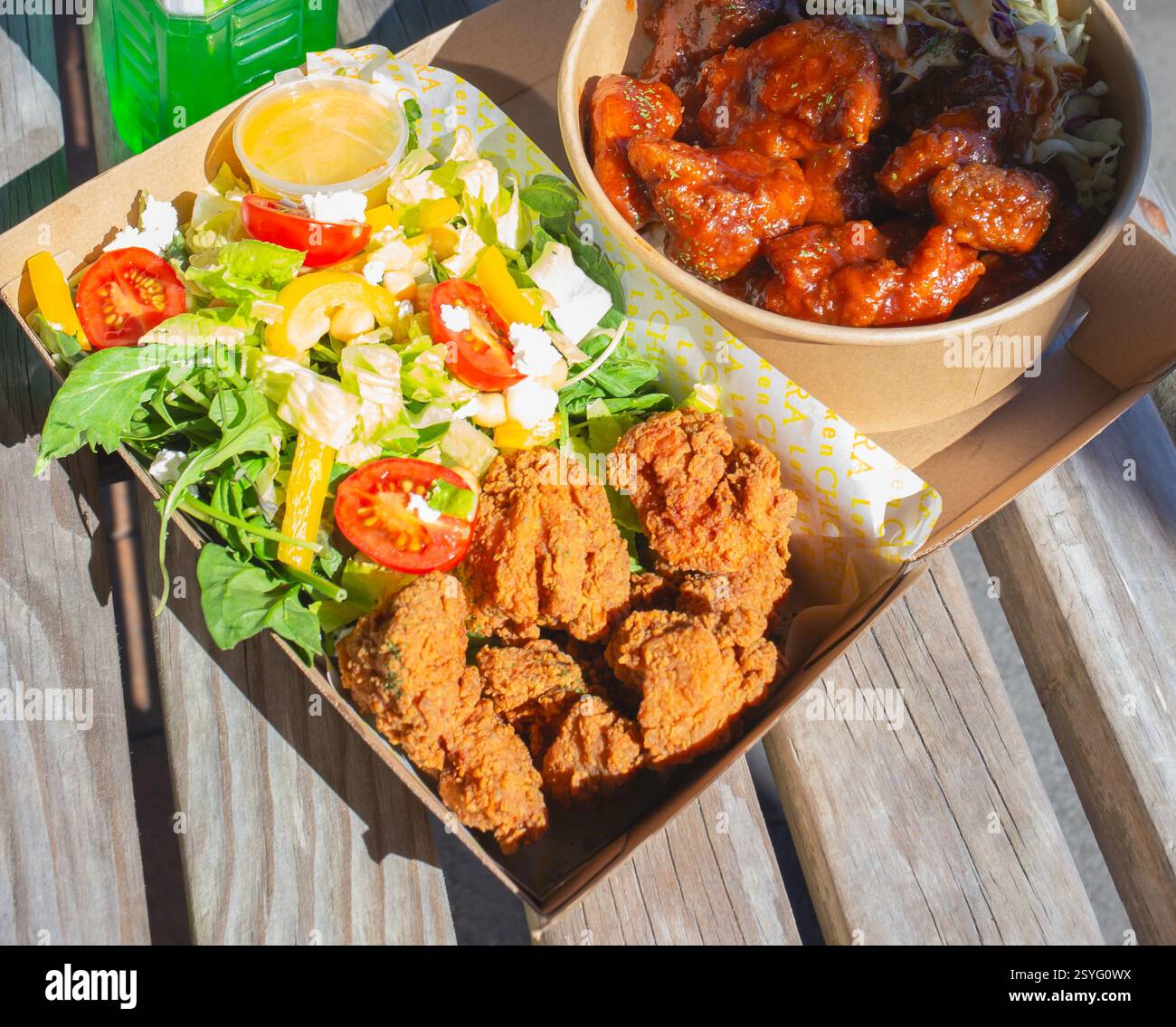 Pollo fritto coreano e insalata in una ciotola di riso su un tavolo bianco con una bevanda verde. Foto Stock