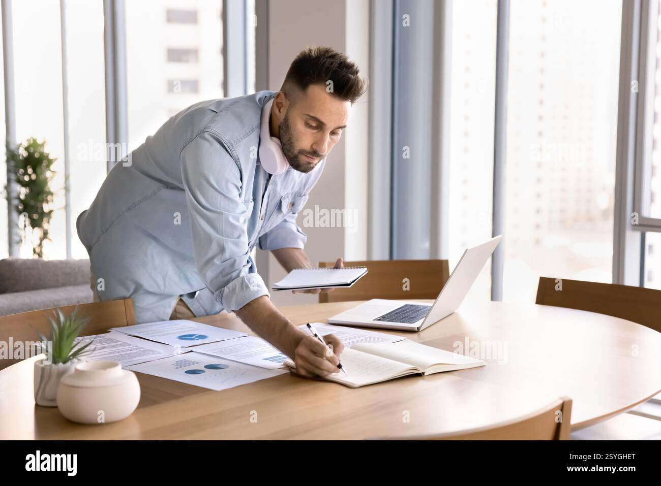 Uomo concentrato che lavora in multitasking e lavora su attività analitiche Foto Stock