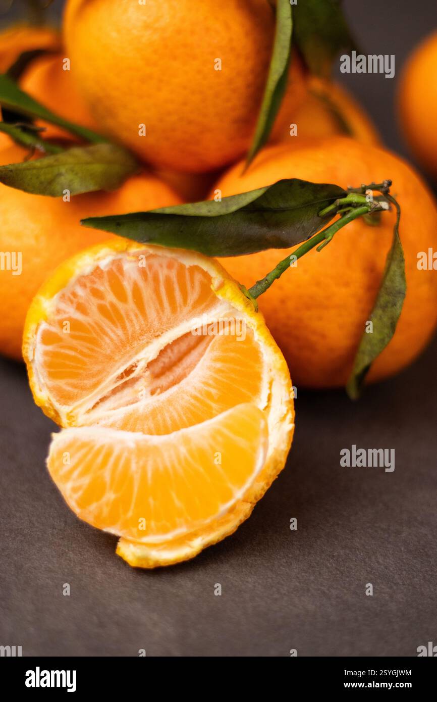 Primo piano di fette di mandarino sbucciate e amalgamare interi mandarini sullo sfondo del tavolo Foto Stock