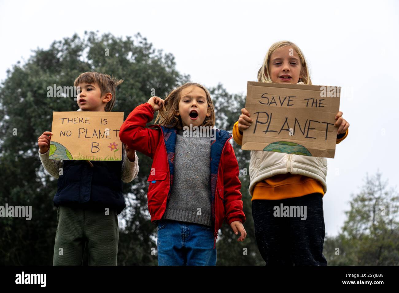 Tre bambini in natura con i segni "Salva il pianeta" e "non c'è pianeta B" Foto Stock