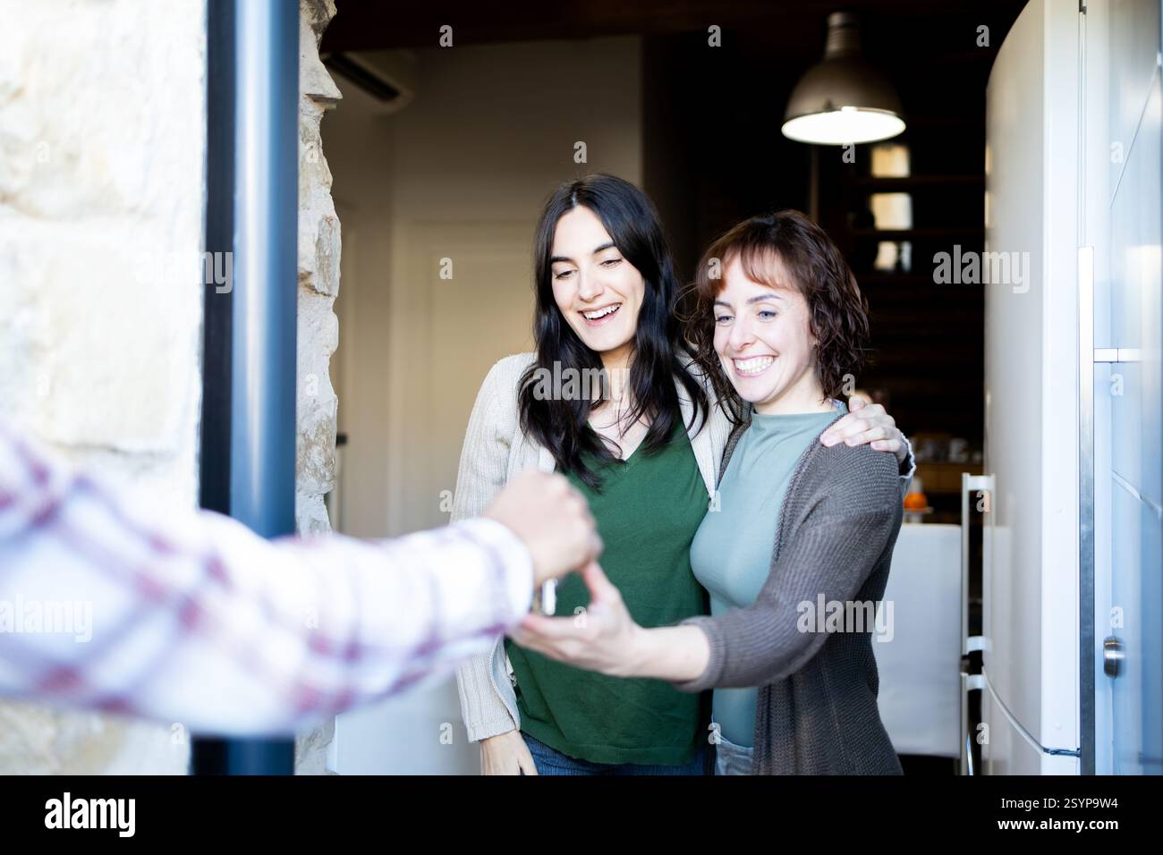 due donne sorridenti ricevono eccitatamente le chiavi della loro nuova casa a due passi. essi esprimono gioia e anticipazione mentre si imbarcano in un nuovo capitolo Foto Stock