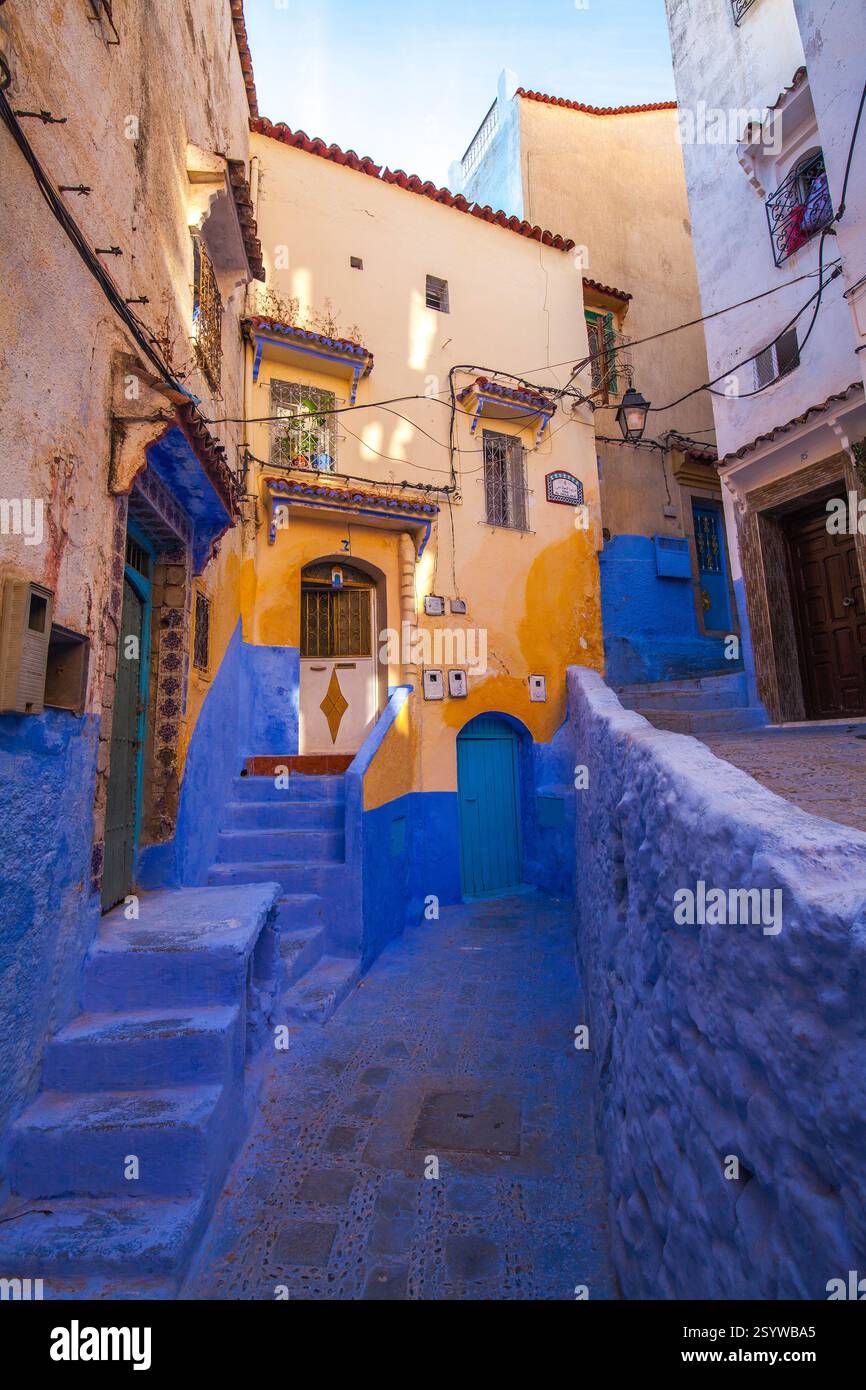 Strada stretta e tortuosa con edifici colorati e pareti e scalini color blu, caratteristica di una città mediterranea Foto Stock