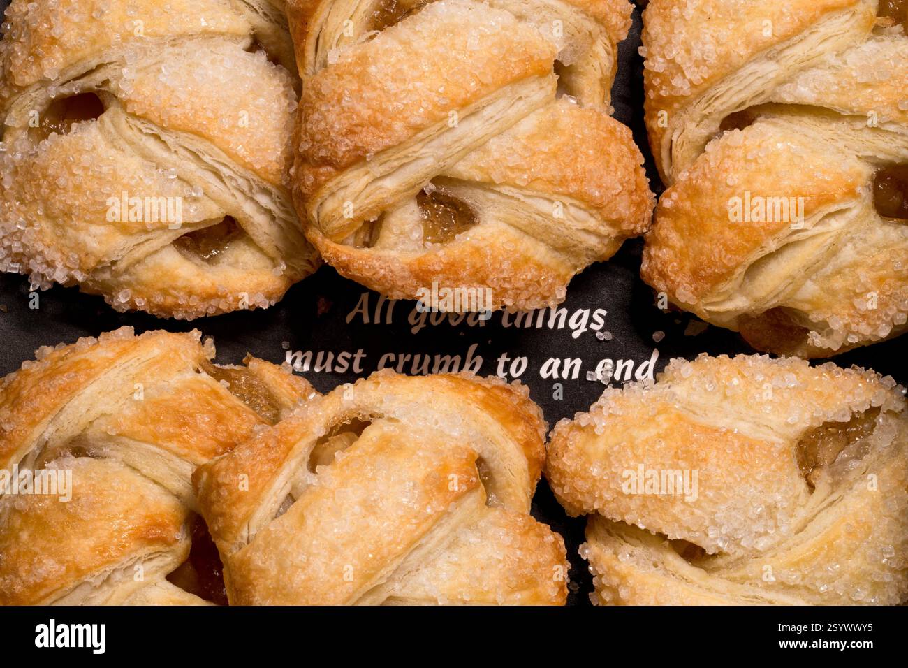 Vista ravvicinata degli strudels di mele appena sfornati con croccante croccante e dorata e una guarnizione di zucchero dolce, disposti su un vassoio da forno scuro Foto Stock