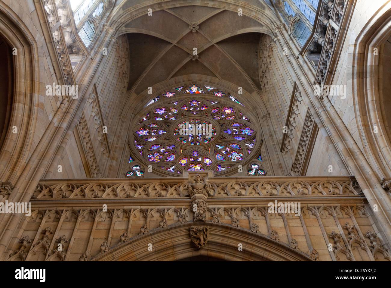 Un'affascinante rosetta con vetrate colorate domina la facciata di una cattedrale gotica, adagiata su uno sfondo di intricati lavori in pietra e così via Foto Stock