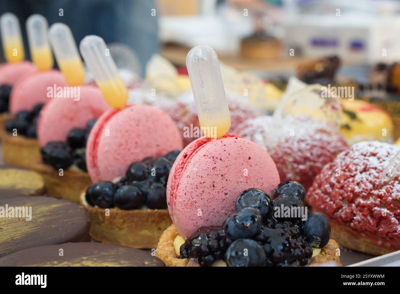 Macaron rosa, crostate e altri dolci. Sciroppo aromatizzato in fase di gocciolamento. Foto Stock