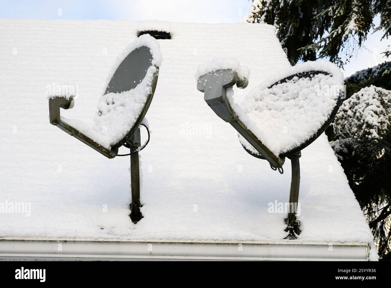 Due antenne satellitari residenziali sul tetto innevato in inverno con ricezione bloccata Foto Stock