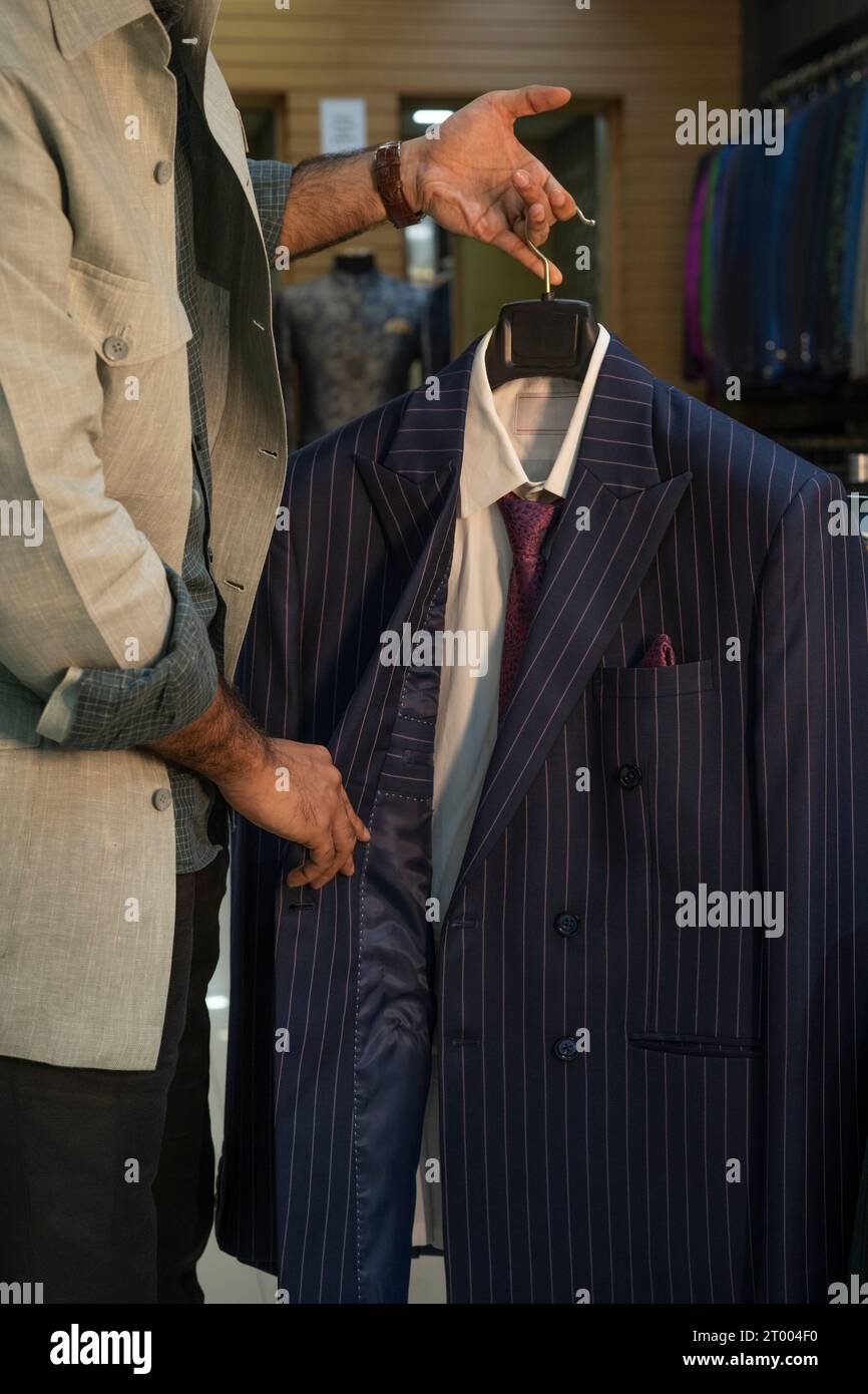 L'acquirente sta controllando le giacche in un negozio di abbigliamento su misura Foto Stock