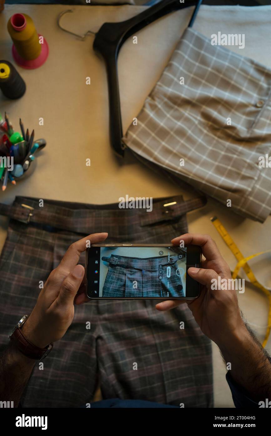 Un giovane professionista che fotografa la sua collezione di abbigliamento Foto Stock