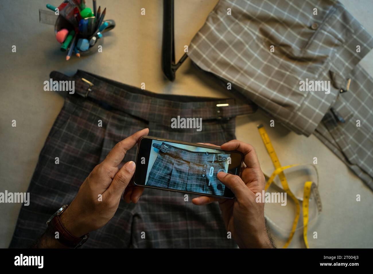 Un giovane professionista che fotografa la sua collezione di abbigliamento Foto Stock