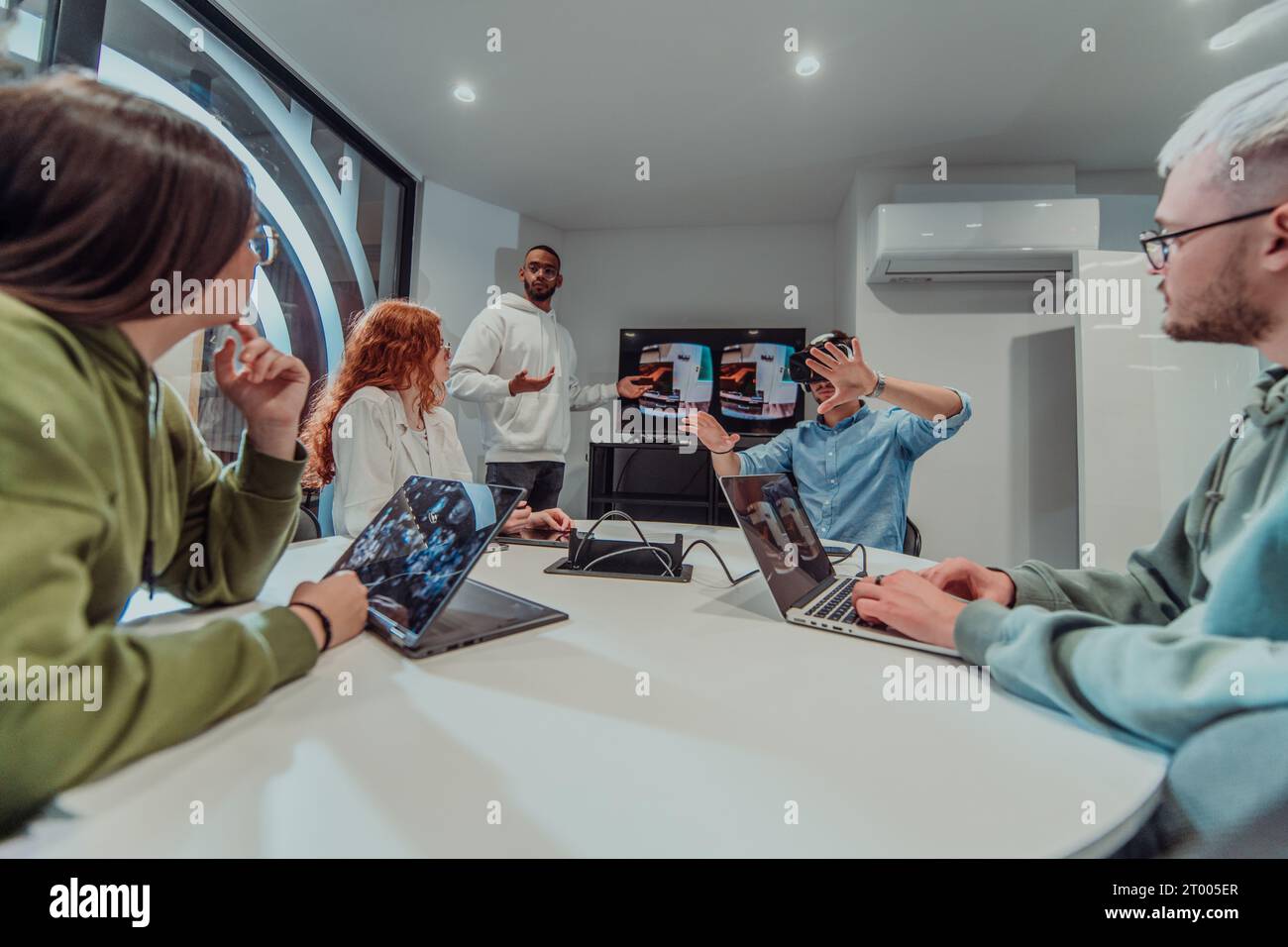 Un gruppo eterogeneo di uomini d'affari collabora e testa una nuova tecnologia di realtà virtuale, indossando occhiali virtuali, mostrando inno Foto Stock