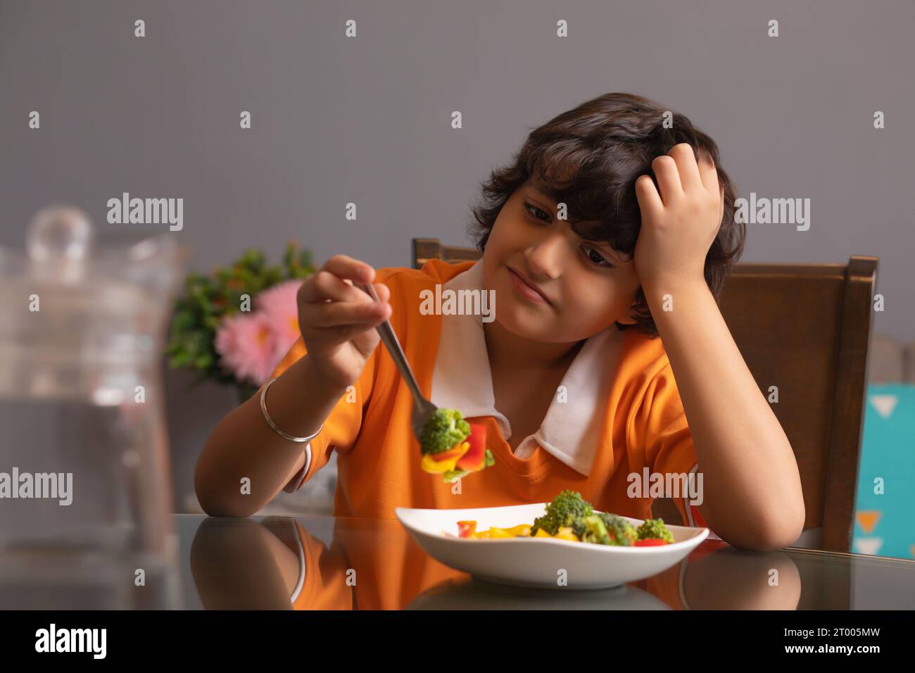 Ritratto di un ragazzo infelice che mangia broccoli Foto Stock