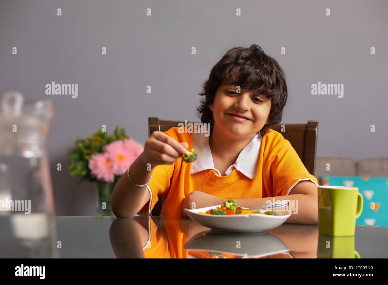 Ritratto di un ragazzo felice che mangia broccoli Foto Stock