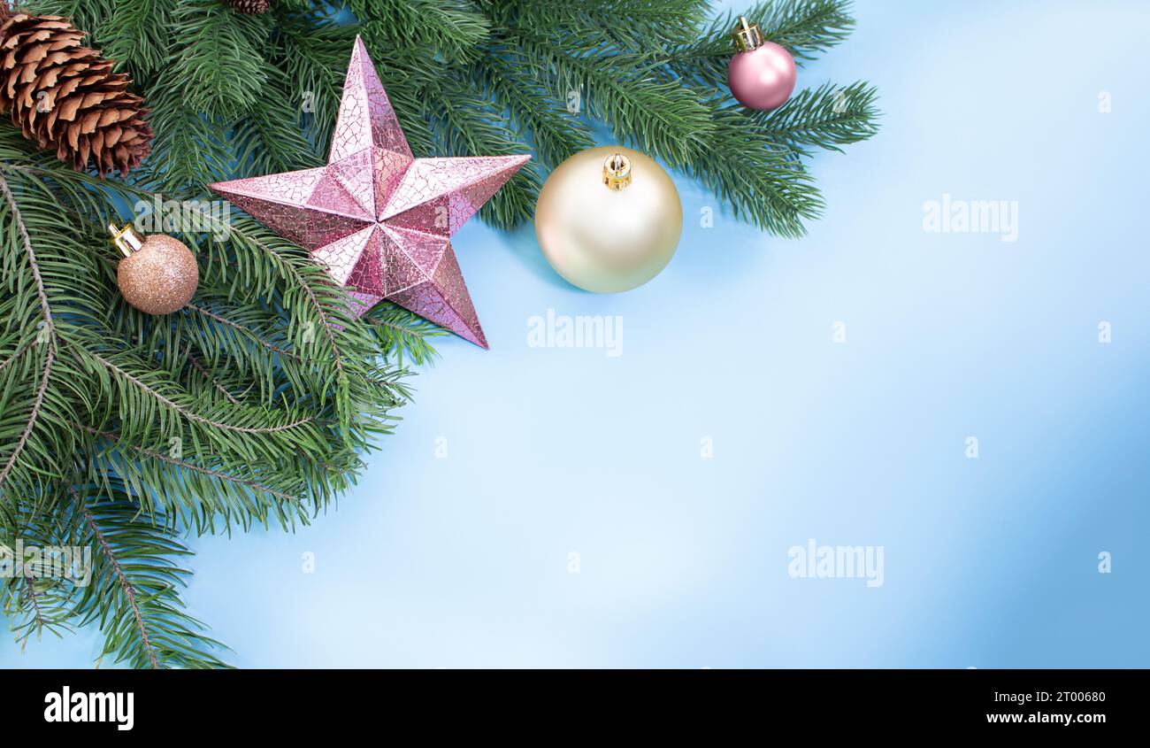 Stella rosa brillante, palle e coni su rami di pino e abete rosso su sfondo blu con spazio per il testo. Natale, anno nuovo. Copia spazio Foto Stock