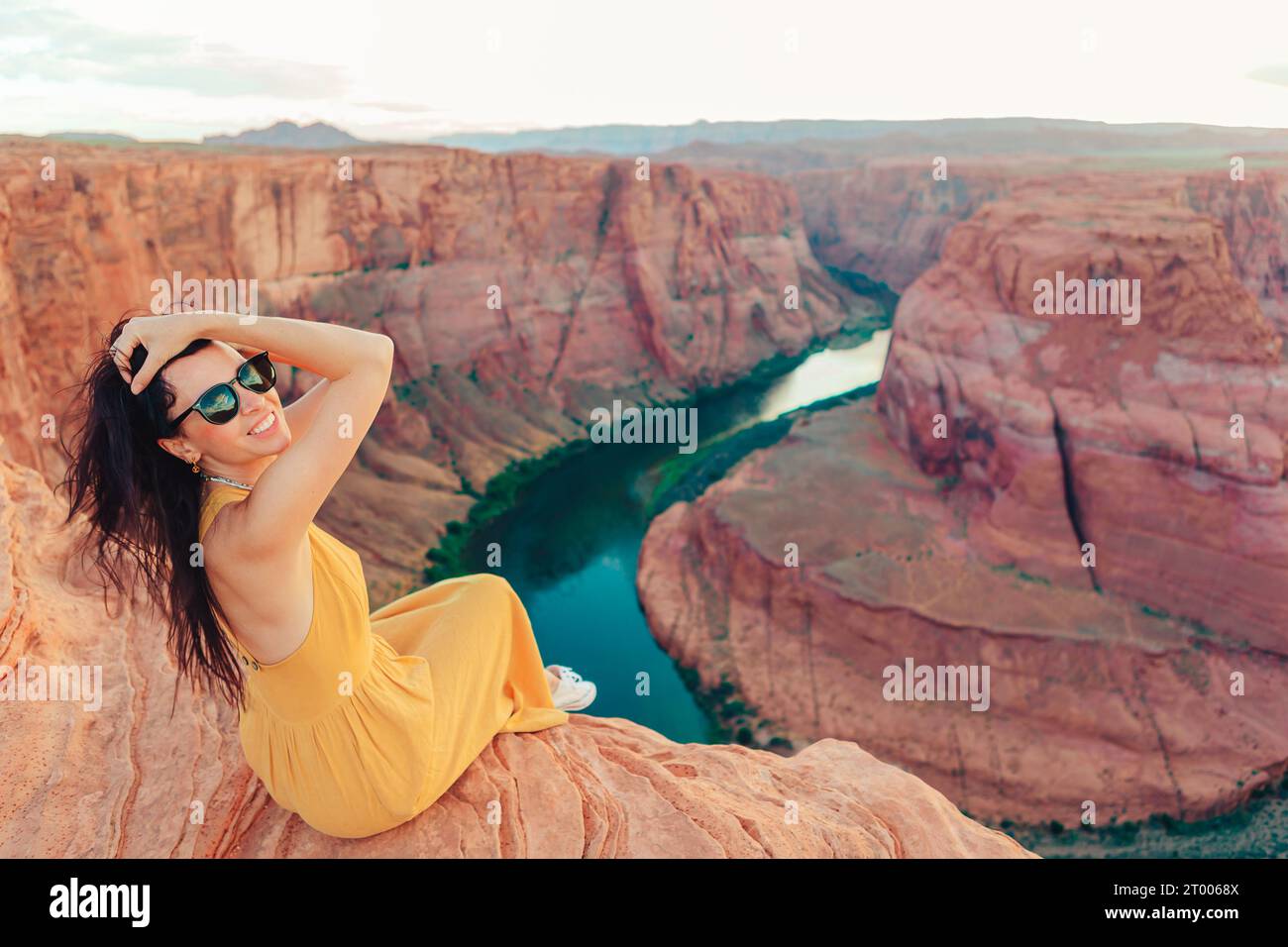 Bella donna in abito giallo sul bordo della scogliera dell'Horseshoe Band Canyon a Paje, Arizona. Splendida natura negli Stati Uniti Foto Stock