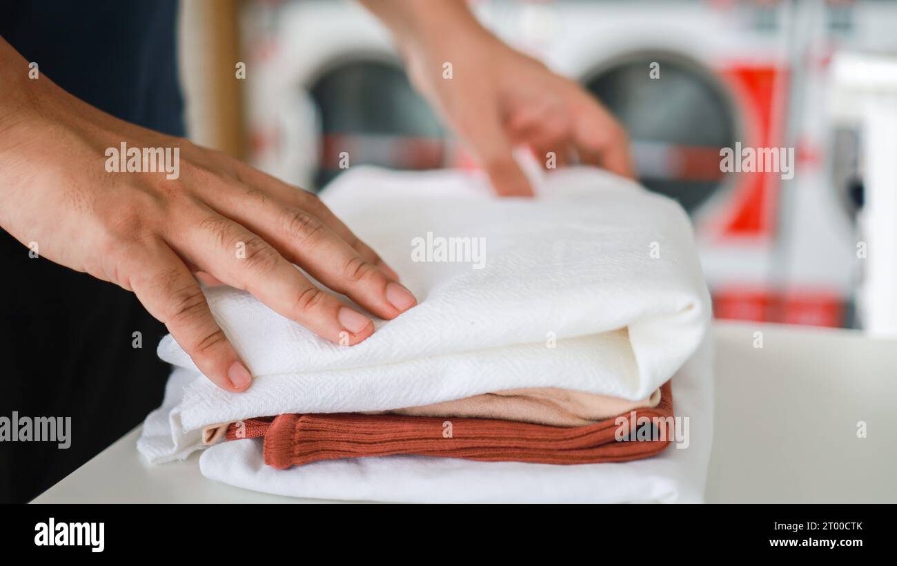 Marito della casa con cesto e vestiti sporchi lavati laundryÂ nell'interno della lavanderia. machineÂ lavatrice presso il negozio di lavanderia Foto Stock