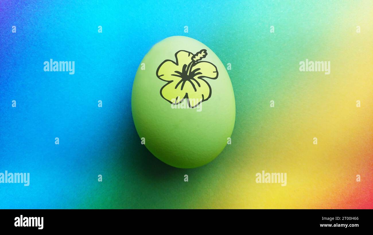 Uovo di pasqua biologico giallo verde con un fiore hawaiano disegnato a mano alla luce del giorno per carte pasquali alternative o qualcosa di cibo biologico Foto Stock