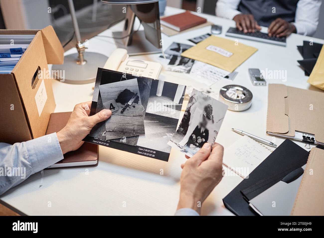 Primo piano del detective maschile che tiene foto con prove durante le indagini, spazio copia Foto Stock