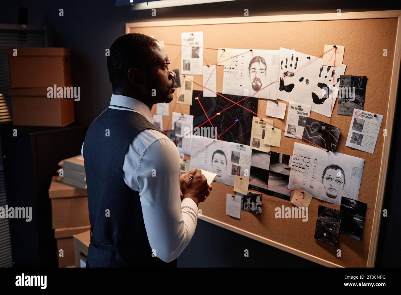 Ritratto drammatico di un detective afroamericano che guarda il Consiglio delle prove in ufficio mentre indaga sul caso, copia dello spazio Foto Stock