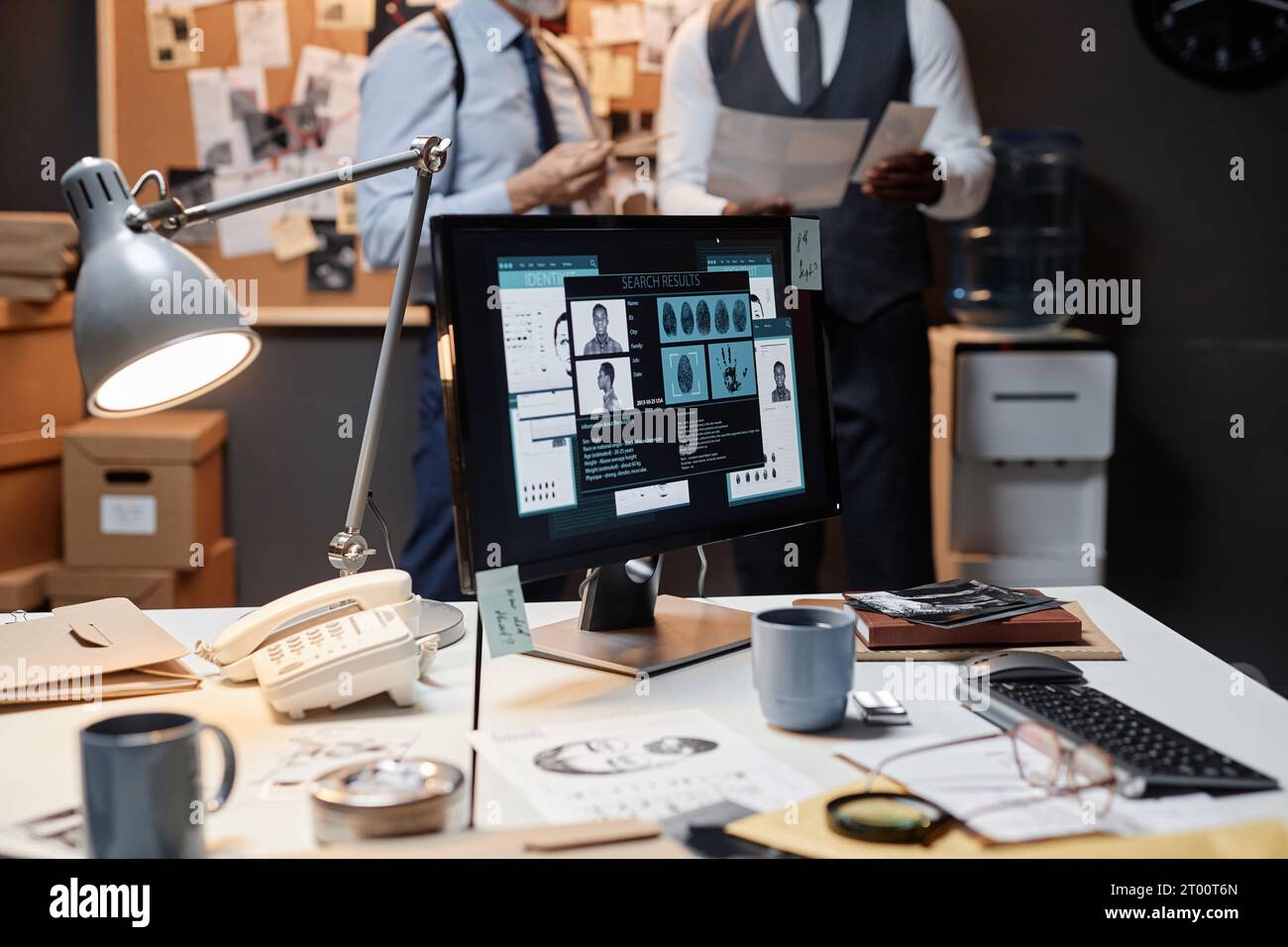 Primo piano della scrivania disordinata nell'ufficio detective con profilo personale sullo schermo del computer, spazio per le copie Foto Stock