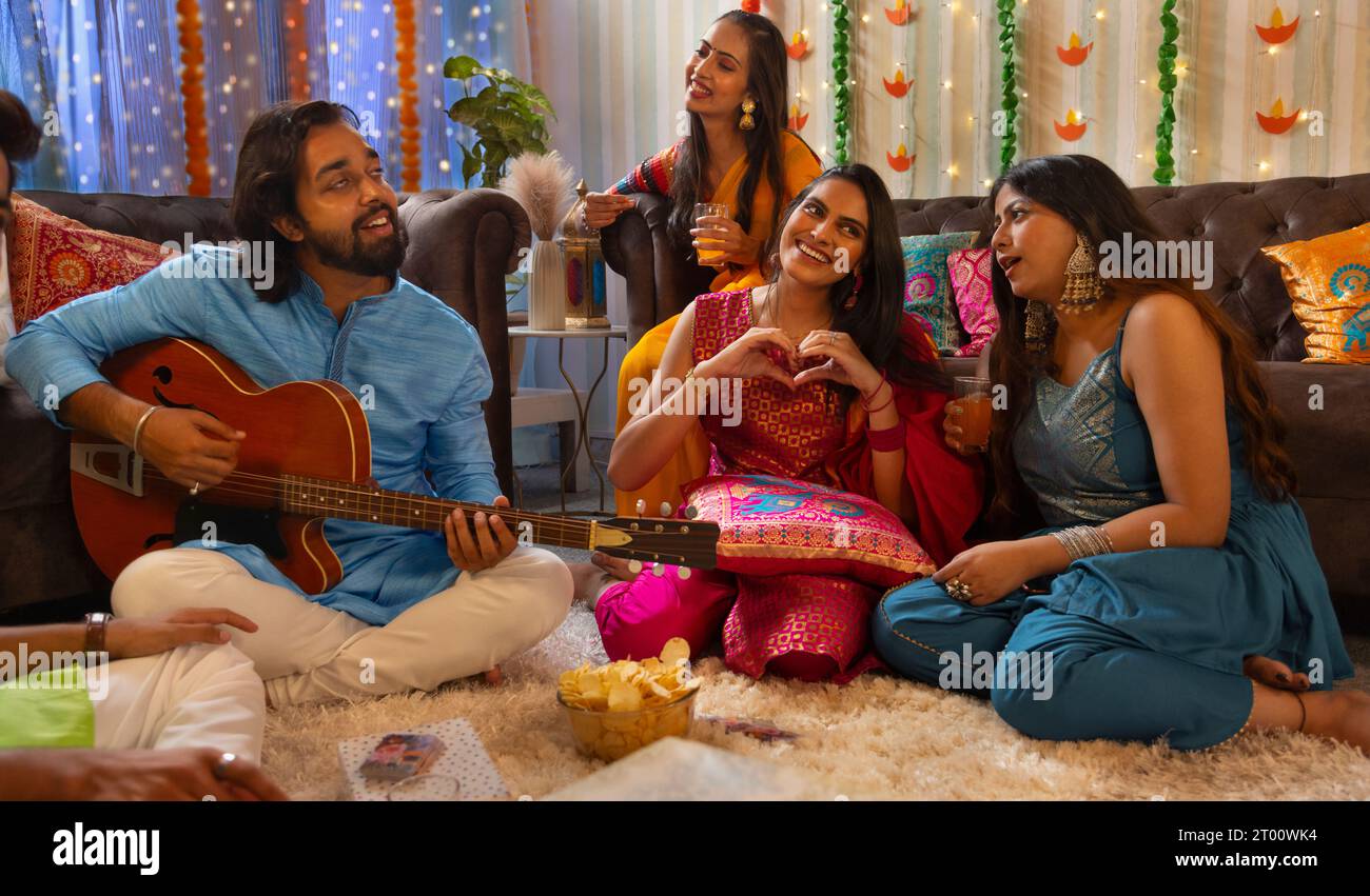 Amici che celebrano Diwali insieme a casa cantando Foto Stock